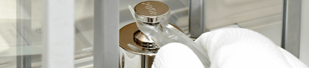 Gloved hand using forceps to place a calibration weight on a digital scale pan Gloved hand using forceps to place a calibration weight on a digital scale pan